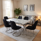 Zurich dining set in a warm family living-dining room — white marble-effect top on chrome X-frames with six black velvet chairs, Amsterdam grey sofa behind