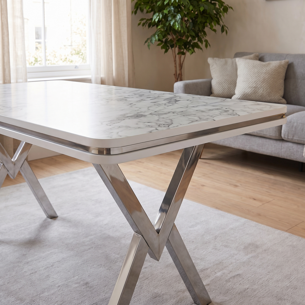 Zurich table detail — white edge band with chrome trim line above a free-standing polished chrome V-frame