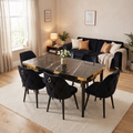 Istanbul dining set in a warm family living-dining room — glossy black marble-effect top with gold lattice apron and six black velvet chairs, Monaco black sofa behind